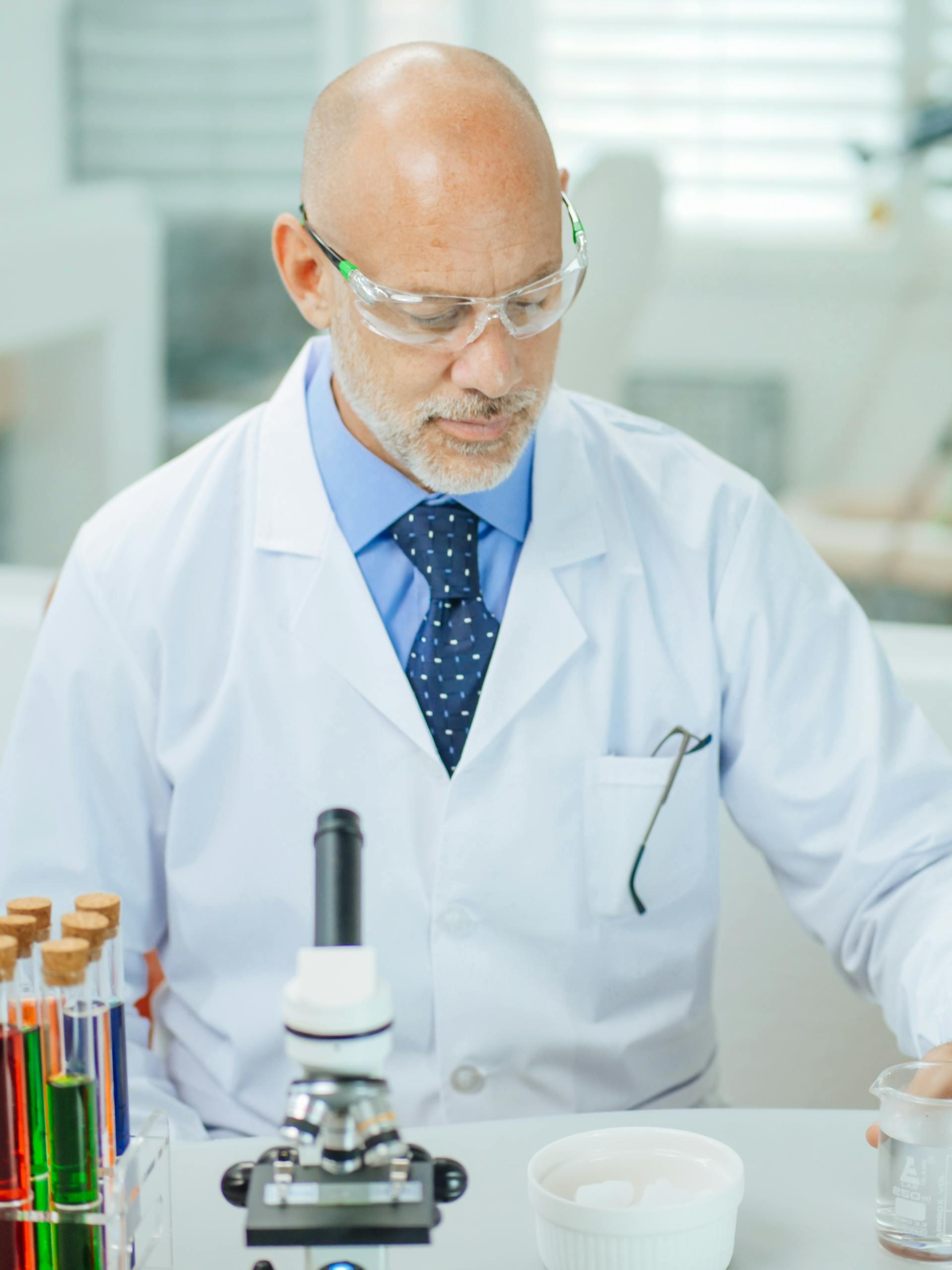 Male scientist analyzing samples in a laboratory setting wearing safety goggles and a lab coat.